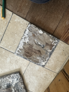 Further exposed section of the bathroom floor showing deteriorated timber beneath the tiled finish. Use as supporting close-up evidence of the condition discovered during opening-up