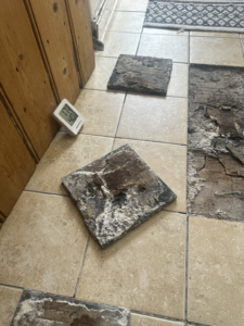 Removed sections of the floor/tiled construction showing the condition of the underlying materials. This supports the narrative that the investigation required removal of sections of the visible finish